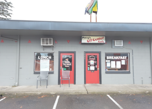 Exterior of Patty's Off-Center Cafe, featuring a gray building with red doors and signs for lunch and breakfast.