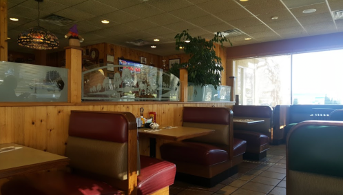 Cozy diner interior with wooden paneling, red booths, and large windows letting in natural light.