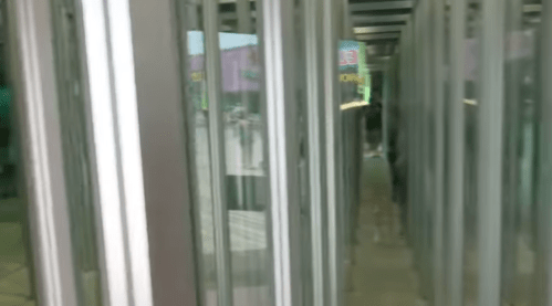A view of a revolving door with glass panels, leading to a bright outdoor area.