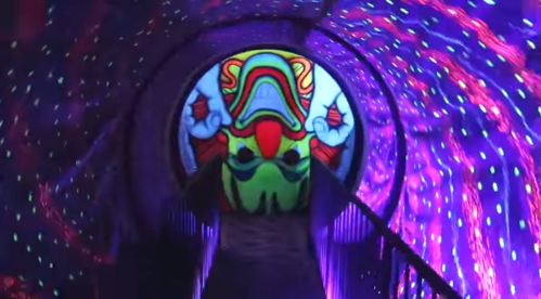 A vibrant, glowing tunnel with colorful patterns and a large, stylized face at the end.
