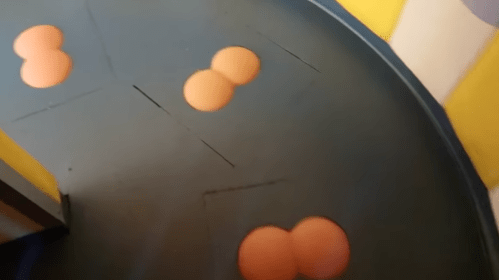 A curved surface with orange circular shapes arranged in a playful pattern against a colorful background.