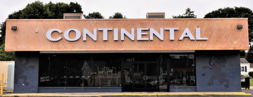 Front view of a building with a wooden facade and large letters spelling "CONTINENTAL" above the entrance.