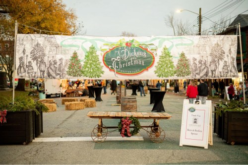 A festive banner for "Dickens Christmas" hangs over a street, with decorations and event setup visible in the background.