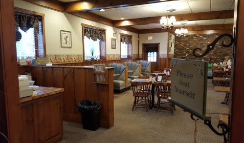 Cozy restaurant interior with wooden decor, tables, and a sign that says "Please Seat Yourself."