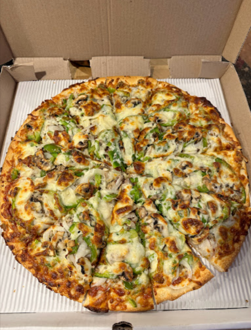 A pizza with green peppers, mushrooms, and melted cheese, cut into slices, in a cardboard box.