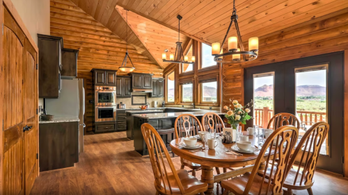 A spacious wooden kitchen and dining area with a large table, modern appliances, and scenic mountain views through windows.