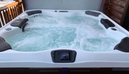 A hot tub filled with bubbling water, featuring a digital temperature display and comfortable seating.