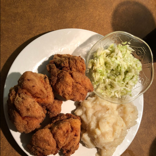 A plate with fried chicken, mashed potatoes, and a side of shredded lettuce.