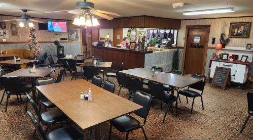 A cozy diner interior with empty tables, a counter in the background, and warm lighting.