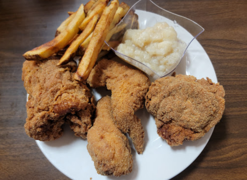 A plate of fried chicken pieces, crispy French fries, and a serving of mashed potatoes.