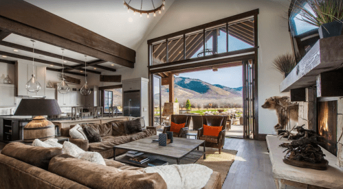 A spacious, modern living room with a cozy sofa, large windows, and a view of mountains outside.