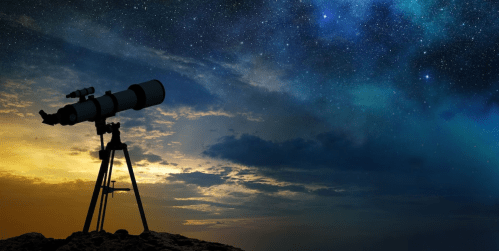 A telescope silhouetted against a starry night sky with colorful clouds at sunset.
