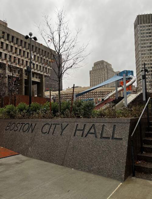 View of Boston City Hall with modern architecture and a cloudy sky in the background.