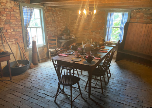 A rustic dining room with a wooden table set for a meal, surrounded by brick walls and vintage decor.