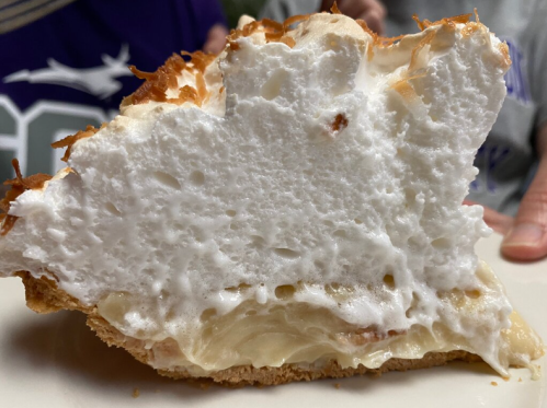 A slice of meringue pie showing a fluffy white meringue topping and a golden crust.