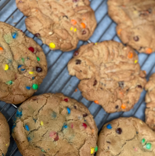 Freshly baked cookies with colorful chocolate chips cooling on a wire rack.