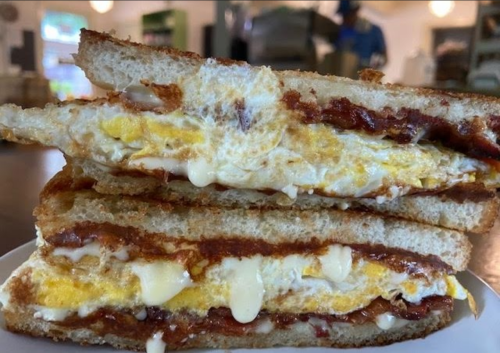 A stacked sandwich with layers of egg, sauce, and melted cheese between toasted bread slices.