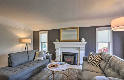 Cozy living room with gray sofas, a marble coffee table, a fireplace, and a large mirror above the mantel.