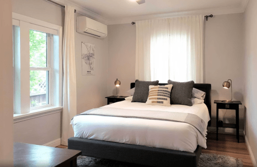 Cozy bedroom with a queen bed, two bedside lamps, and large windows letting in natural light.
