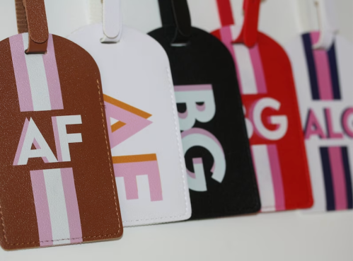 A close-up of colorful luggage tags in various colors and designs, featuring bold letters and stripes.