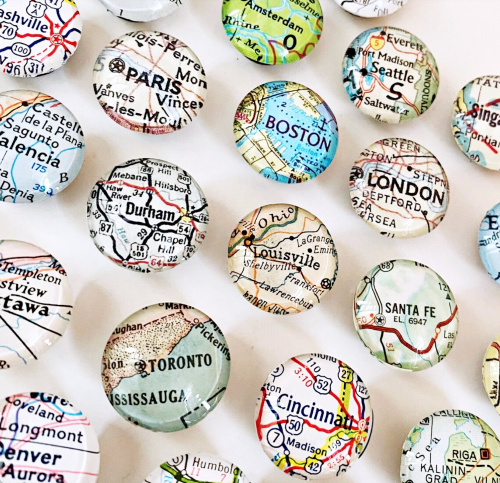A collection of glass map pins featuring city names from various locations around the world.