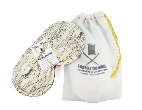 A pair of handmade sleep masks with a map design, accompanied by a drawstring pouch featuring the brand logo.