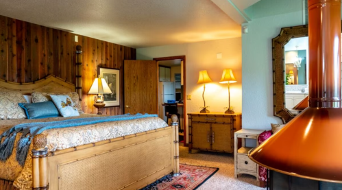 Cozy bedroom with a wooden bed, warm lighting, and a decorative fireplace, creating a welcoming atmosphere.