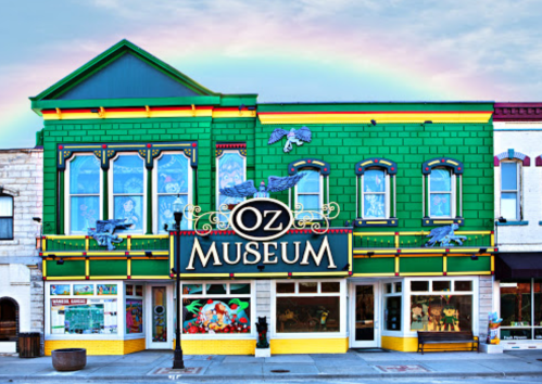 Colorful Oz Museum building with a rainbow in the background, featuring whimsical decorations and signage.
