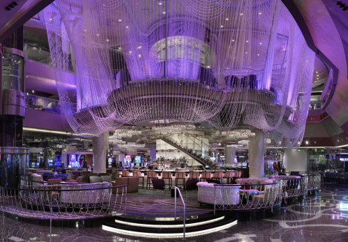 A luxurious casino interior featuring a grand chandelier, elegant seating, and vibrant purple lighting.