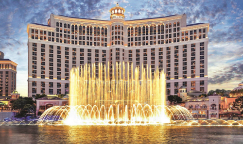 The Bellagio Hotel with a vibrant fountain display in front, set against a dramatic sky.