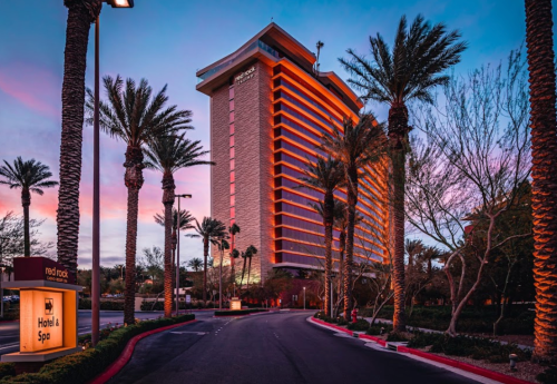 A tall hotel with palm trees at sunset, featuring warm lighting and a welcoming entrance.
