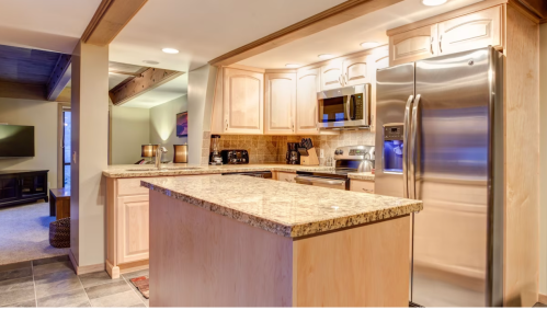 Modern kitchen with granite countertops, stainless steel appliances, and warm lighting. Open layout with a cozy atmosphere.