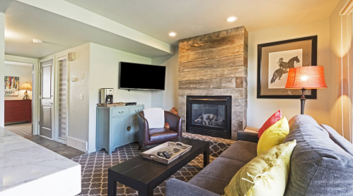 Cozy living room with a fireplace, modern furniture, and a large TV, featuring warm colors and stylish decor.