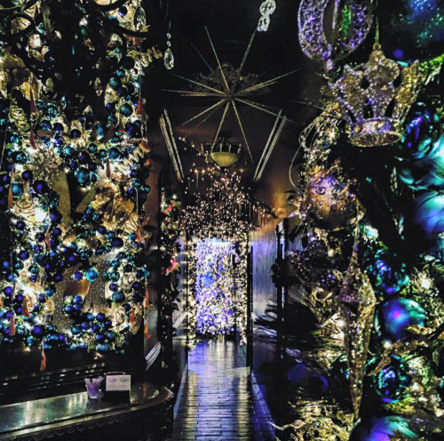 A festive hallway adorned with blue and silver decorations, sparkling lights, and Christmas trees.