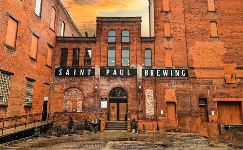 Exterior of Saint Paul Brewing, featuring a brick building with large windows and a sign above the entrance.
