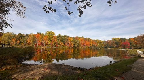 A serene lake surrounded by vibrant autumn foliage under a clear blue sky.