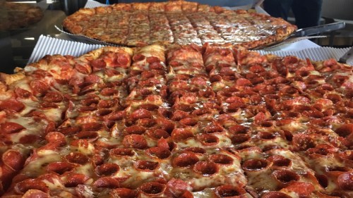 Two large pizzas, one topped with pepperoni and the other with cheese, displayed on a table.