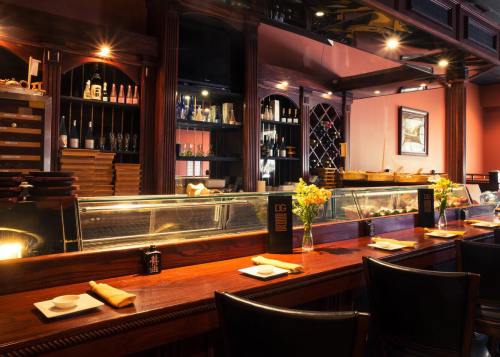 A cozy restaurant interior featuring a wooden bar, shelves of wine, and elegant table settings with flowers.