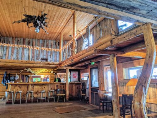 Cozy wooden interior of a rustic bar with a warm atmosphere, featuring a wooden bar and seating area.