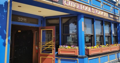 Blue exterior of Two Fools Tavern in New Mexico with gold trim, flower boxes, and a traditional pub entrance.