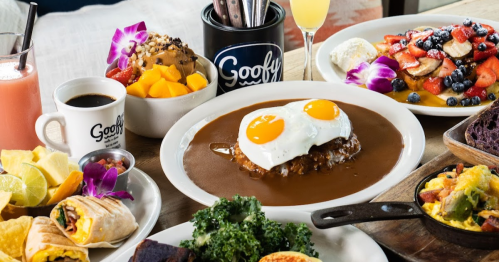 A vibrant brunch spread featuring eggs, fruit, coffee, and various dishes on a wooden table.