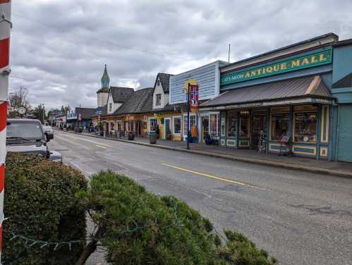 A quaint street lined with colorful shops and an antique mall under a cloudy sky.