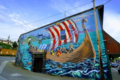A colorful mural of a Viking ship sailing on water, painted on the side of a building.