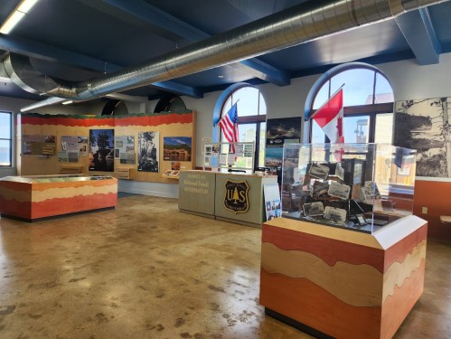 Interior of a visitor center with displays, flags, and informational panels about the surrounding area.