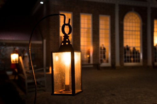 A glowing lantern hangs in the foreground, illuminating a building with warm, lit windows in the background.