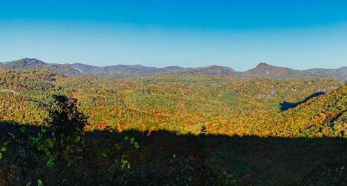 A panoramic view of a colorful autumn landscape with rolling hills and clear blue skies.