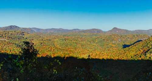 A panoramic view of a colorful autumn landscape with rolling hills and clear blue skies.