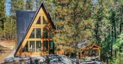 Looking toward an A-frame cabin Airbnb surrounded by a pine tree forest in Garden Valley, Idaho.