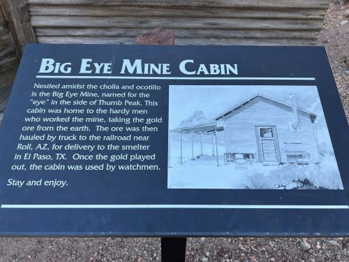 Sign describing the Big Eye Mine Cabin, detailing its history and connection to gold mining in the area.