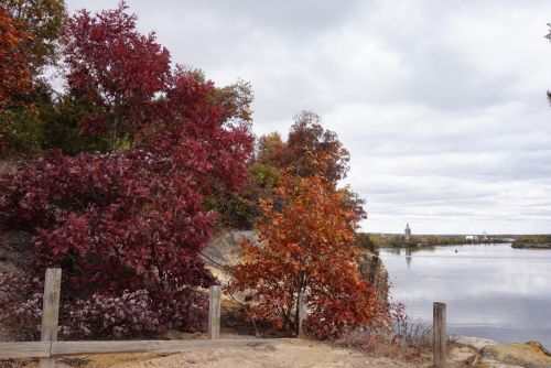 A serene river scene with colorful autumn trees and cloudy skies, reflecting the vibrant fall foliage.